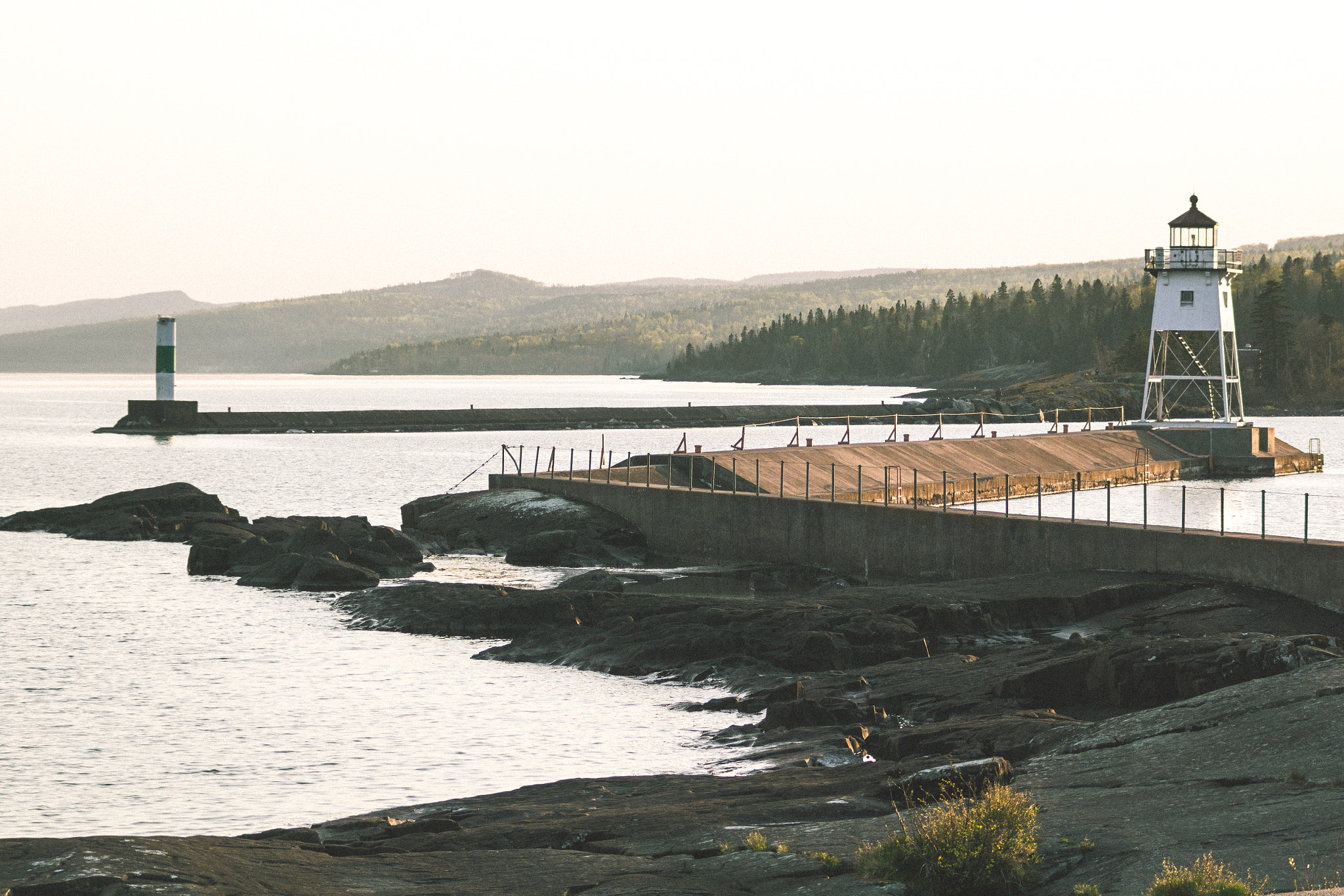 Grand Marais lighthouse and harbor breakwaters beside rocky Lake Superior shore