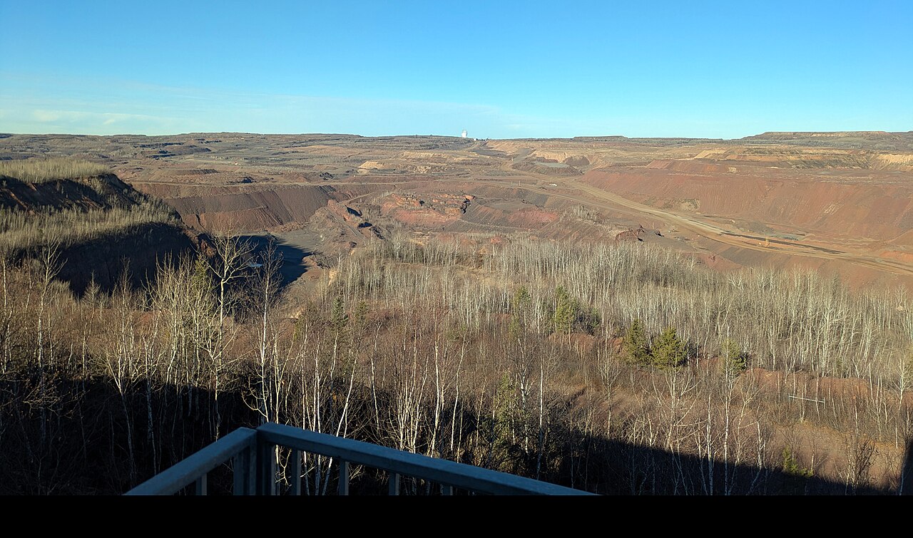 Terraced open-pit mine beyond trees at the Hull-Rust-Mahoning visitor viewpoint