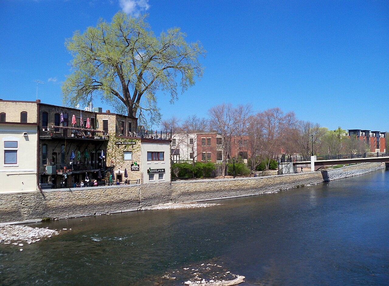 Cannon River beside downtown Northfield buildings and a pedestrian bridge