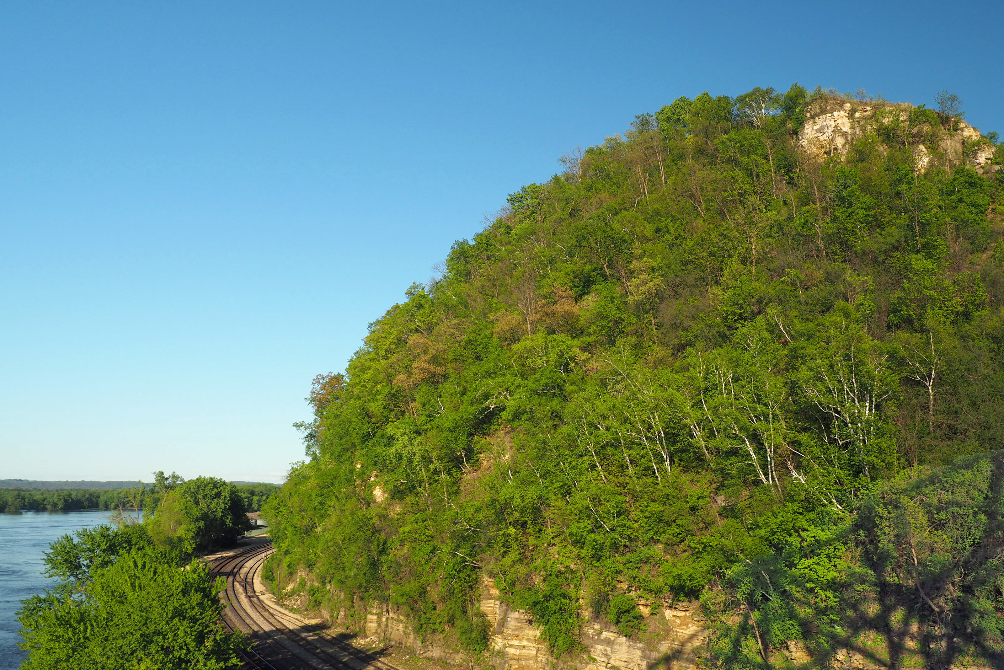 Wooded Barn Bluff rising beside the Mississippi River and railroad tracks in Red Wing